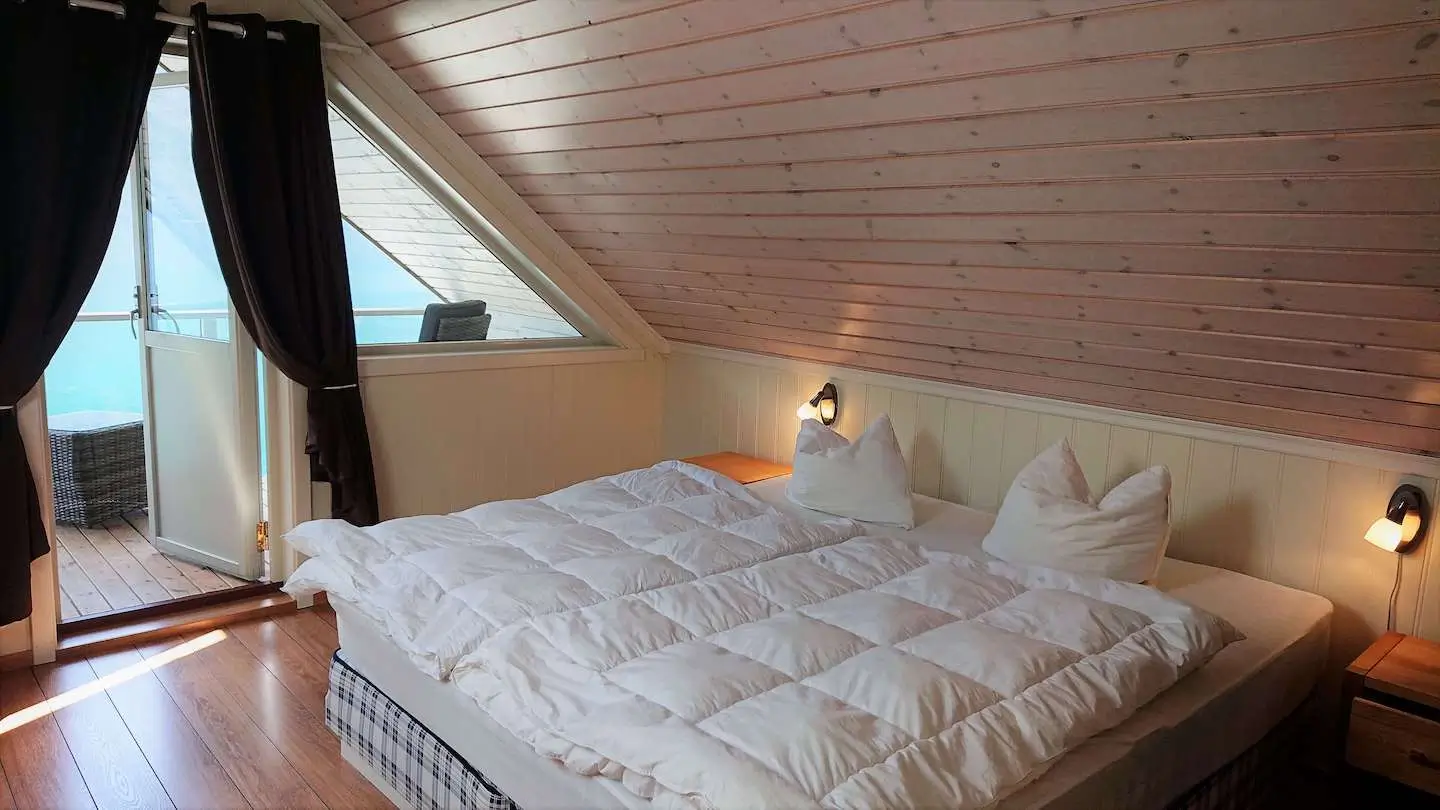 Utsikt frå hyttevindauget mot ein blikkstille fjord i morgonlys